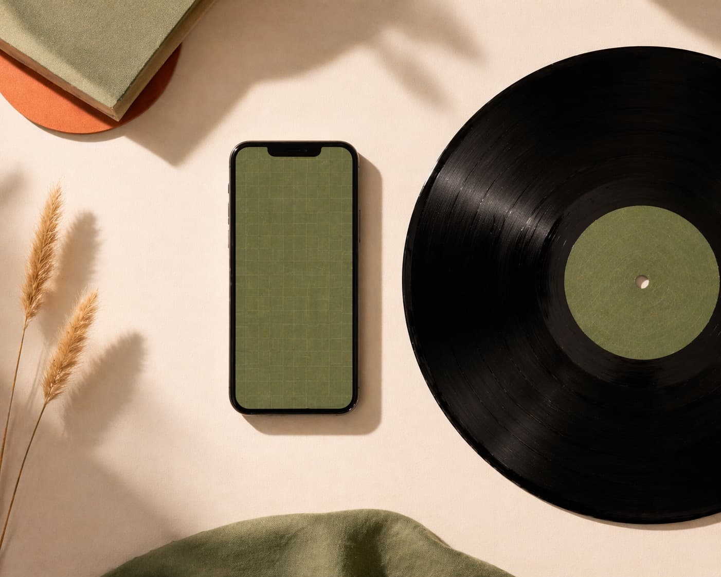 Minimalist flat lay of a smartphone with a green grid and a vinyl record on a cream background